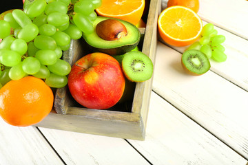 Assortment of fruits in box on wooden table