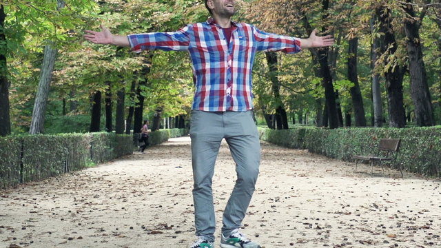 Happy man turning around in park during autumn