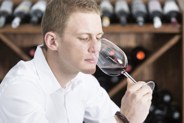 young man smelling a glass of red wine.