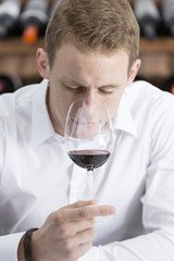 young man smelling a red wineglass.