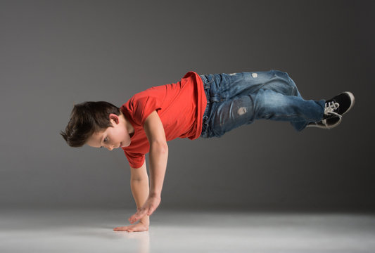 little break dancer showing his skills on grey background.