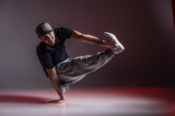 young break dancer showing his skills on grey background.