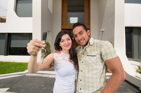 happy couple holding key to their new house