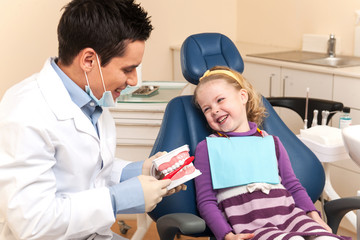 Little girl is having her teeth examined by dentist.