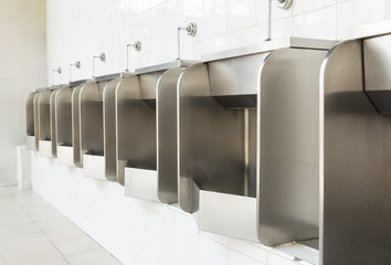 Row of stainless urinals at public restroom