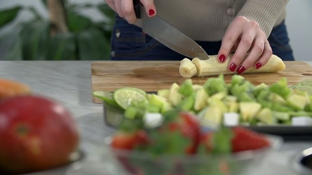 Slicing banana into pieces for smoothie in slow motion