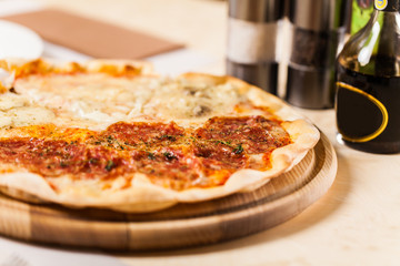 Pizza with bottle and pepeer and salt on wooden table.