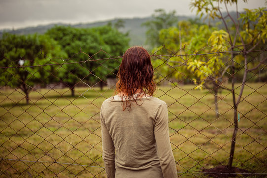 Young woman by fence on farm