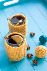 Two cups of tea in yellow Knitted sweaters on blue background