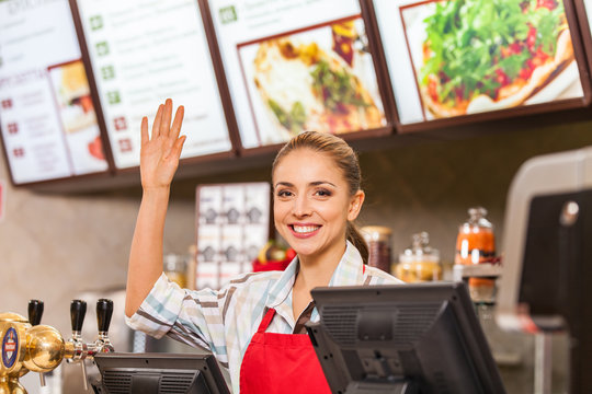Restaurant worker at cashier smiling at work place.