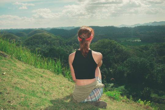 Young woman sitting on a hill and admiring view