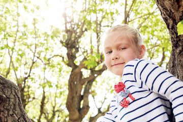 cute girl sitting on a tree in summer