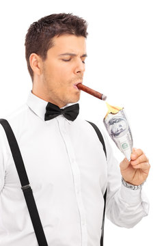 Rich man lighting up a cigar with burning dollar