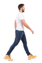 Young man walking in jeans and white t-shirt - obrazy, fototapety, plakaty