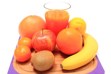 Fresh natural fruits and glass of juice on cutting board