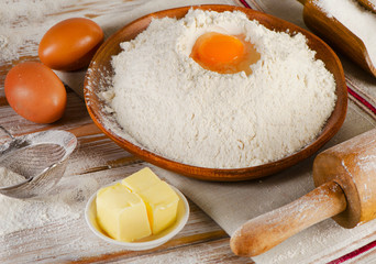 Eggs, flour, sugar and butter on a white  wooden background