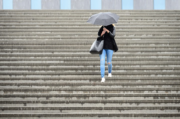 Young adult woman walks down the stairs in the rain