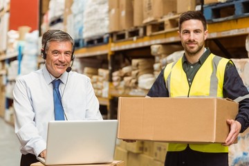 Smiling warehouse manager using laptop