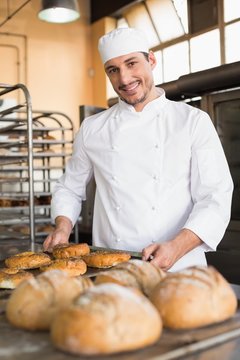Happy baker taking out fresh bagels