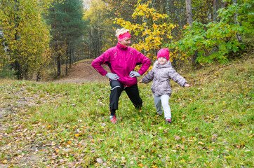 Fototapeta premium Woman with girl doing aerobics in the autumn park