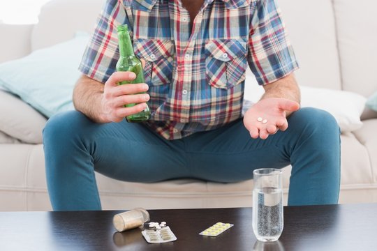 Man with a beer and his medicine laid