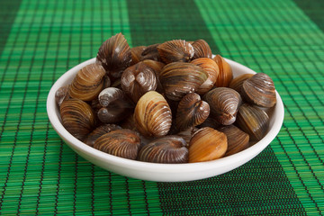 A plate with uncooked mussels on a green mat