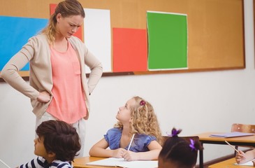 Angry teacher looking pupil with hands on hips