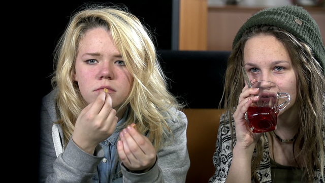 Girls sip tea dn eat snack at the end of their seats