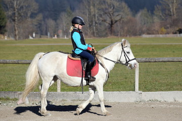 junges Mädchen reitet auf Pferd