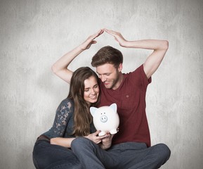 Composite image of couple sitting on floor with piggy bank