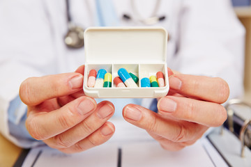 Arzt zeigt Pillenbox mit Medikamenten