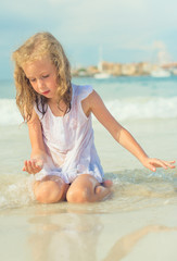 Little girl playing with sand on the beach.