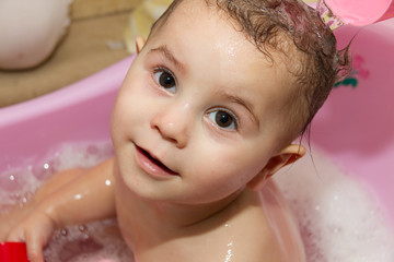 Cute little girl bathes in a shower