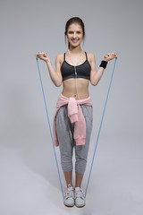 Full length portrait of a happy sporty woman with skipping rope