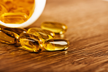 Pills spilling out of a jar on a wooden surface