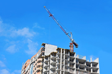 Crane and building construction site against blue sky