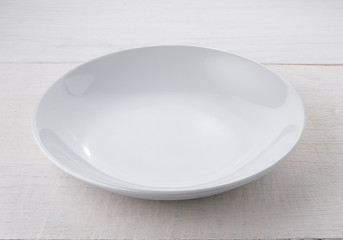 Empty white plate on wooden table