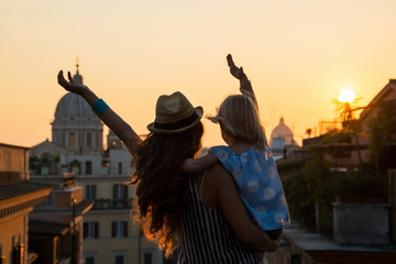 Naklejka premium Silhouette of mother and baby girl looking on rooftops of Rome