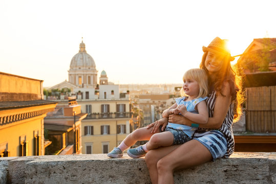 Mother and baby girl sitting on street  in Rome