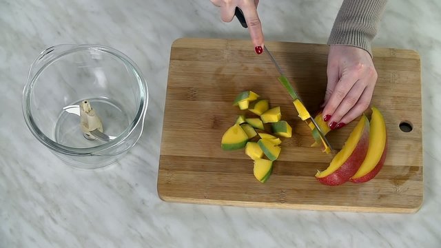 Slicing mango into small pieces with large knife