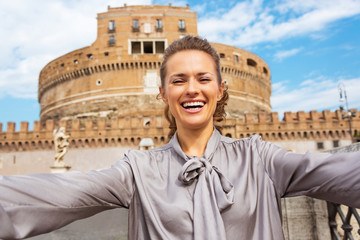 Happy young woman making selfie in front of castel sant'angelo