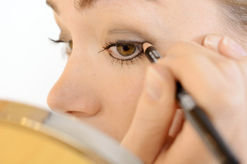 Frau schminkt Auge mit Eyeliner und Kajalstift