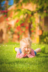 Plakat Marvelous little girl plays with on green spring grass