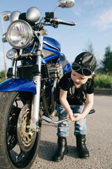 Fototapeta na wymiar little biker repairs motorcycle on road