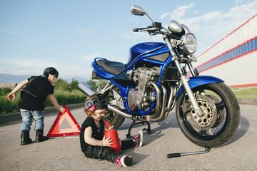 Obraz premium mały rowerzysta naprawia motocykl na drodze