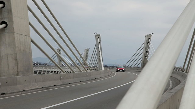 Car drving across bridge and shooting from windshield