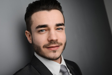 portrait of young business man posing in front of gray wall