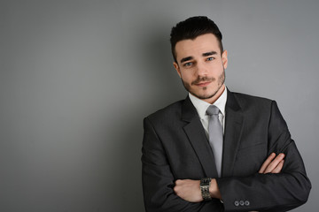 portrait of young business man posing in front of gray wall