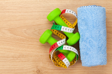 Dumbells and tape measure over wooden table with copy space