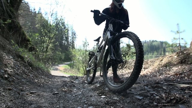 Downhill driver push the bike on a mud road